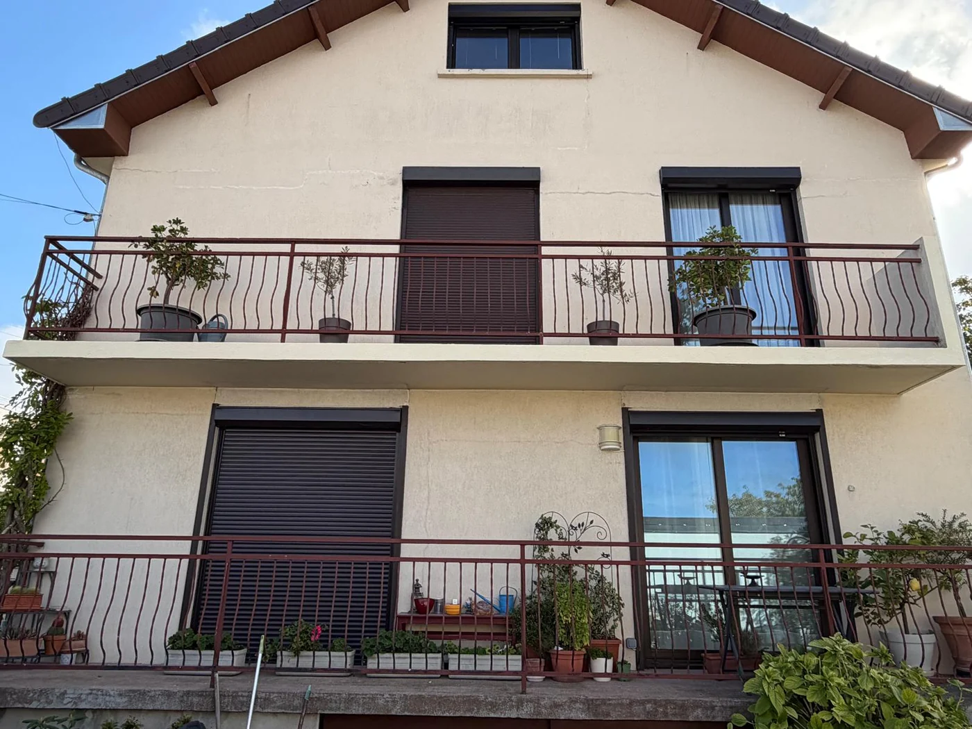Façade d’une maison à deux niveaux avec couverture sombre.