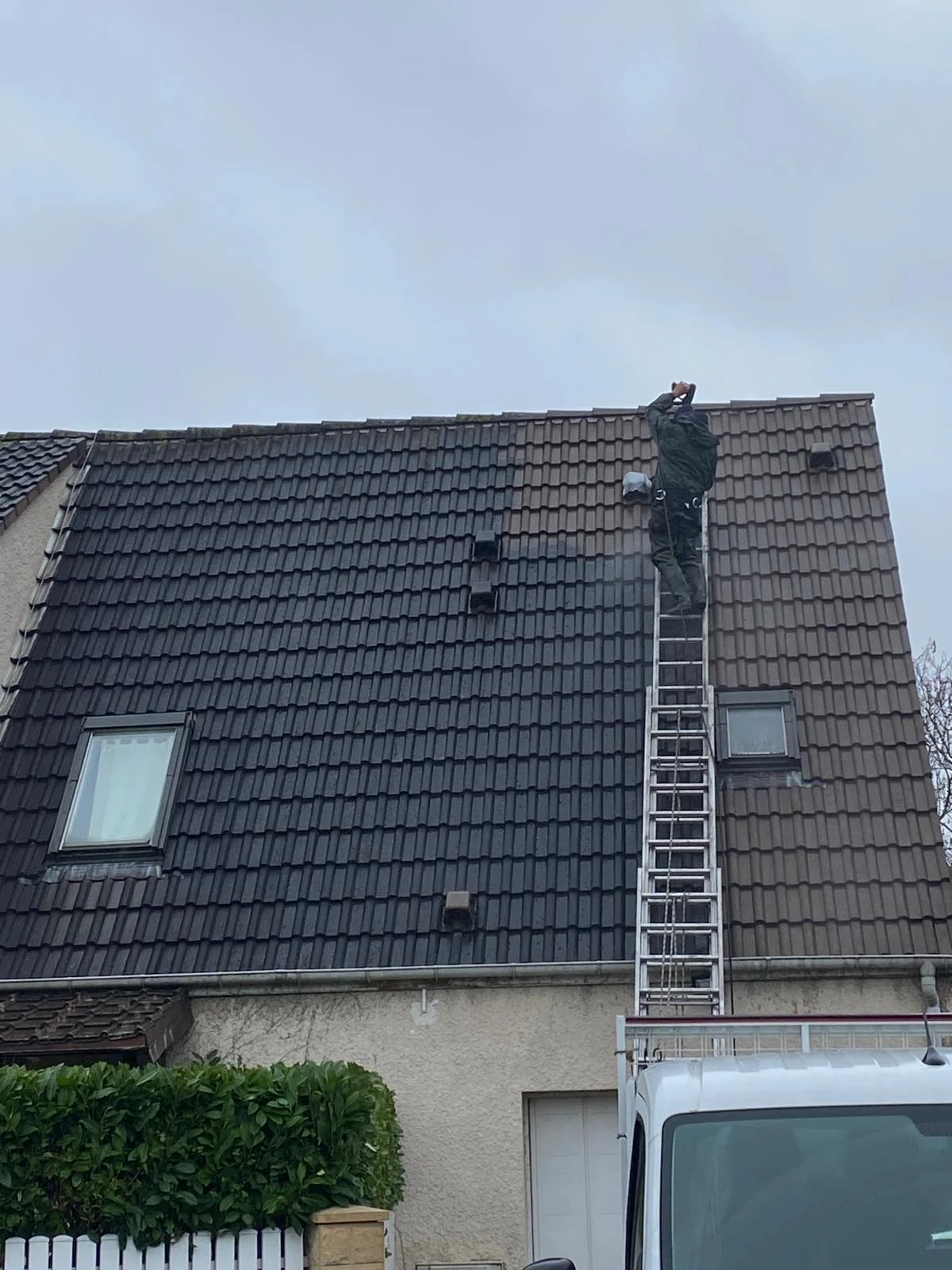 Couvreur intervenant sur une toiture en tuiles.