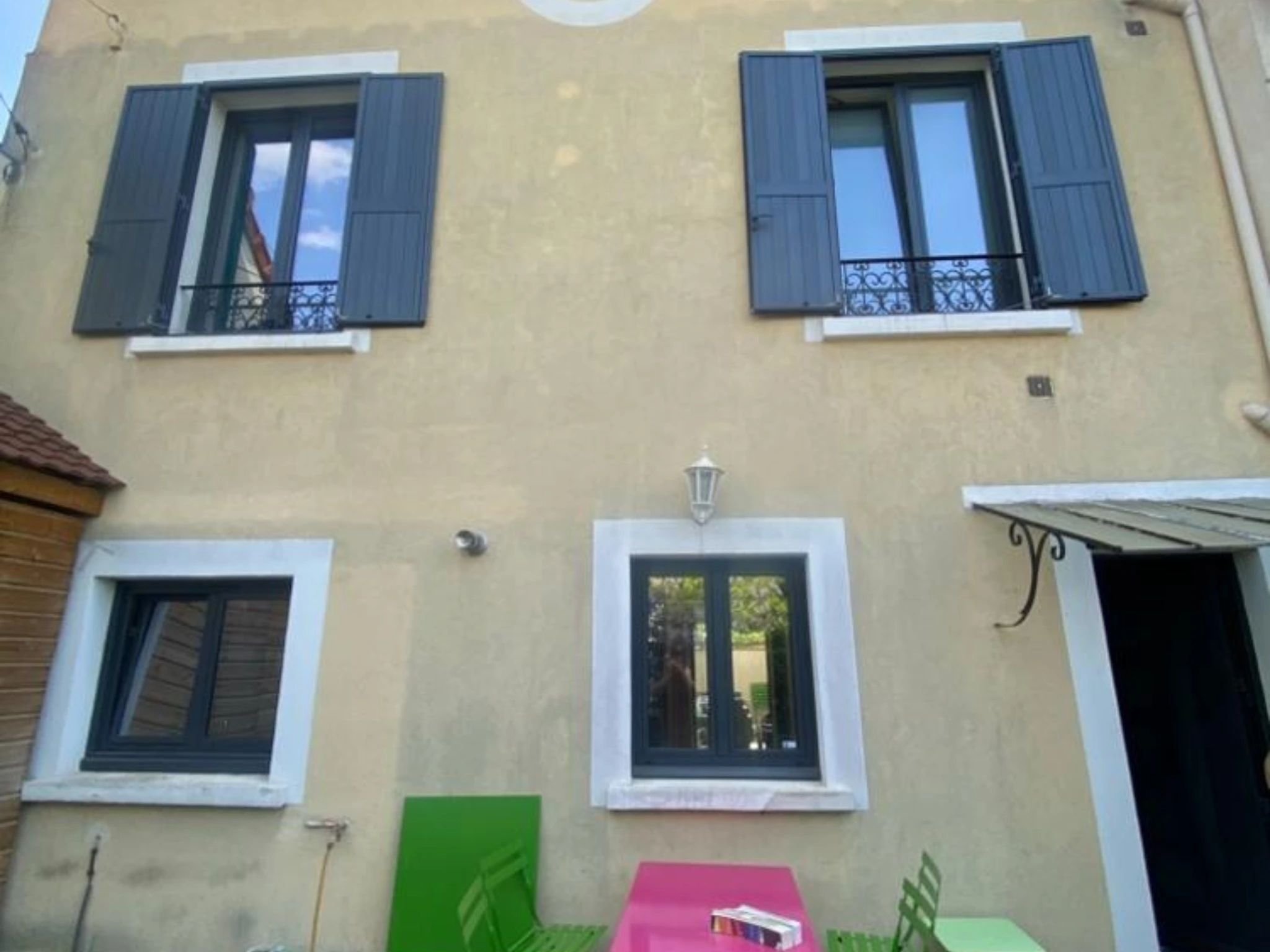 Façade en briques peintes avant le ravalement : peinture écaillée, soubassement taché, panneau de chantier GARCIA.J sur la grille